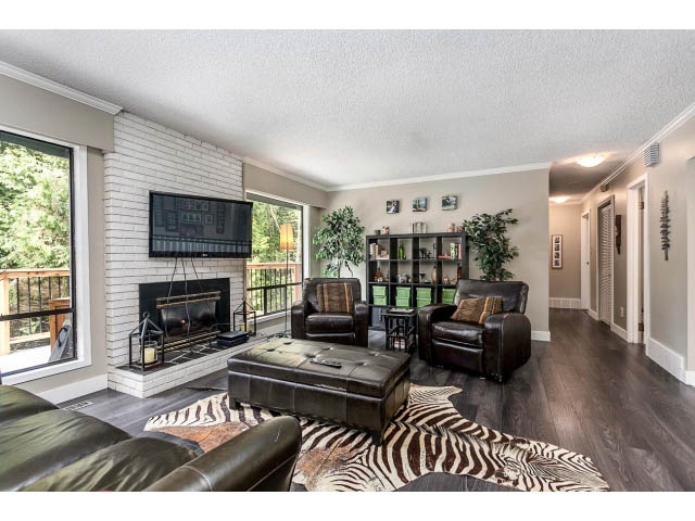 Furnished living room with zebra print rug, leather furniture, and brick fireplace. - 3243 Milton Ave., North Vancouver