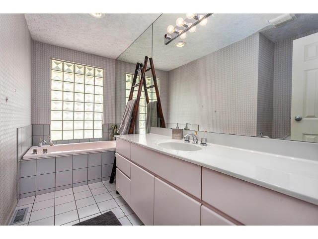Bright bathroom with white tile walls, large mirror, and modern sink fixtures. - 3243 Milton Ave., North Vancouver