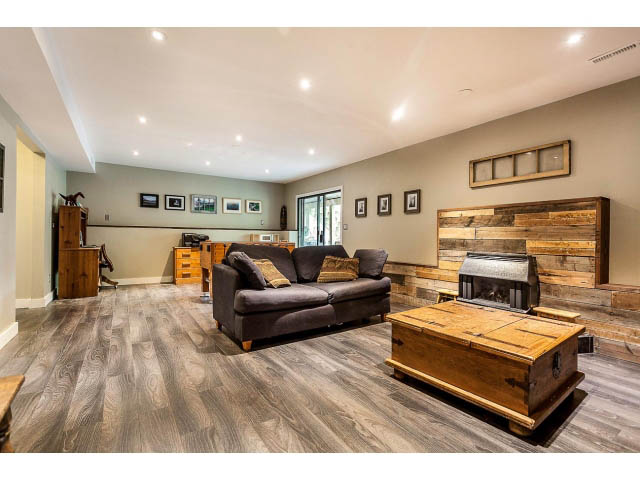 Furnished living room with hardwood floors and rustic decor, featuring a large sectional and wooden furniture. - 3243 Milton Ave., North Vancouver