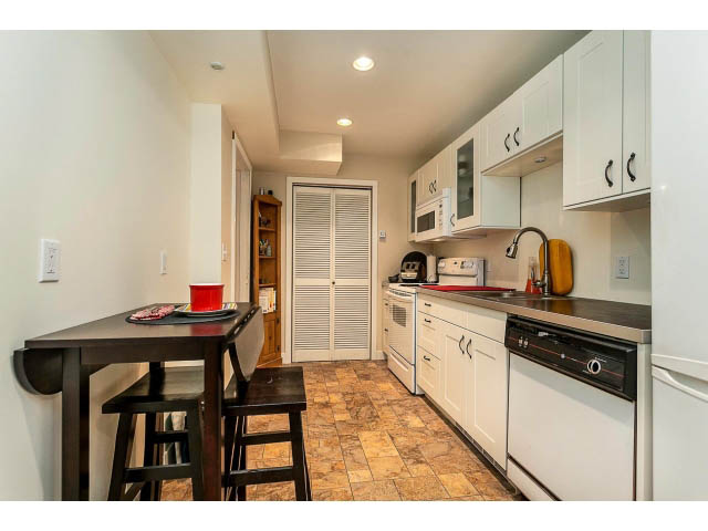 Bright kitchen with white cabinets, dark countertops, and tiled flooring. - 3243 Milton Ave., North Vancouver