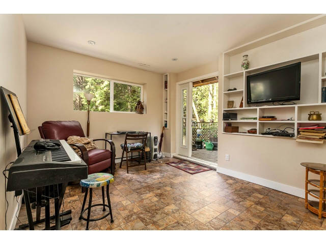 Bright living room with tiled floors, built-in shelves, and a large window. - 3243 Milton Ave., North Vancouver