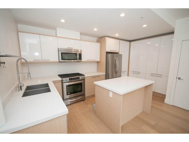 Bright kitchen with white countertops, stainless steel appliances, and hardwood floors. - 3187 St. George St., Vancouver East Side