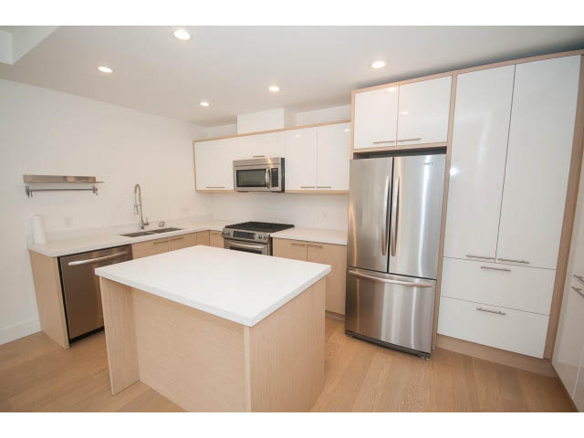 Bright kitchen with white cabinets, stainless steel appliances, and light wood flooring. - 3187 St. George St., Vancouver East Side