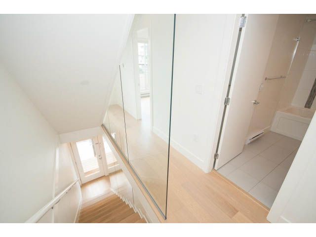 Bright hallway with hardwood floors and glass railings leading to the second floor. - 3187 St. George St., Vancouver East Side