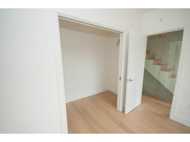 Bright living room with hardwood floors and a glass staircase leading to the upper level. - 3187 St. George St., Vancouver East Side