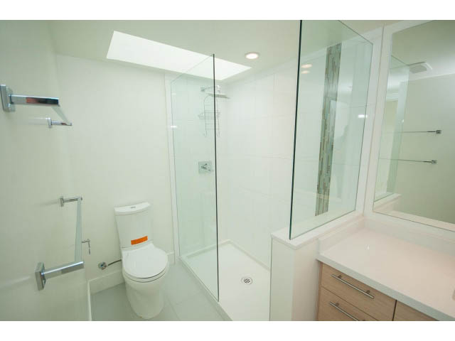 Modern bathroom with glass shower, white countertop, and sleek fixtures. - 3187 St. George St., Vancouver East Side