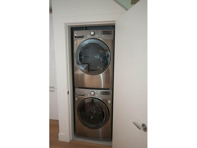 Bright laundry room with stacked washer and dryer, modern design. - 3187 St. George St., Vancouver East Side