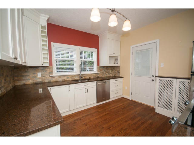 Bright kitchen with granite countertops, hardwood floors, and a red accent wall. - 5756 Angus Drive, Vancouver West Side