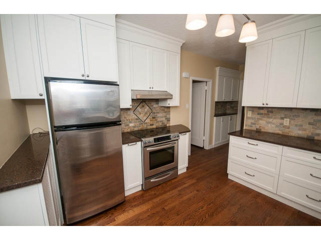 Bright kitchen with granite countertops, hardwood floors, and white cabinetry. - 5756 Angus Drive, Vancouver West Side