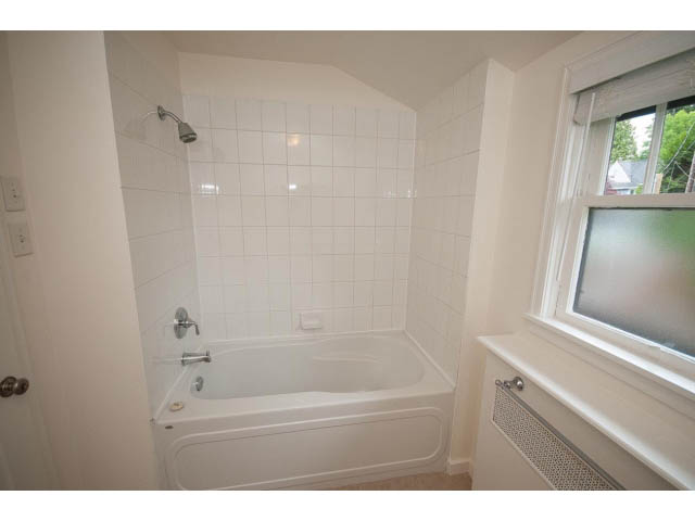 Bright bathroom with white tile, corner tub, and window view. - 5756 Angus Drive, Vancouver West Side