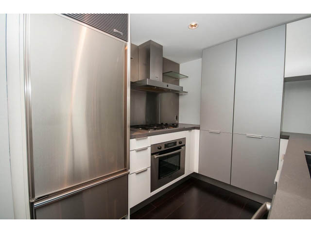 Bright kitchen with stainless steel appliances and white cabinetry, featuring hardwood floors and a modern design.