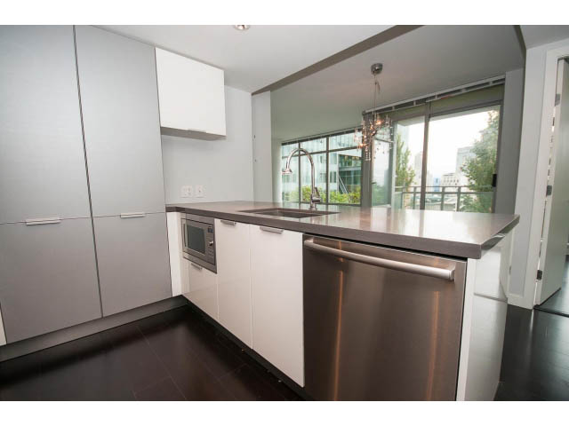 Bright kitchen with modern stainless steel appliances and sleek countertops, featuring a city view through large windows.