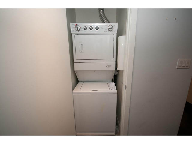 Laundry area with stacked washer and dryer, white walls, and utility door. - 1106 - 788 Richards, Vancouver Downtown