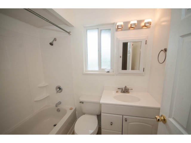 Bright bathroom with white fixtures, large mirror, and natural light from windows. - 549 W Queens, North Vancouver