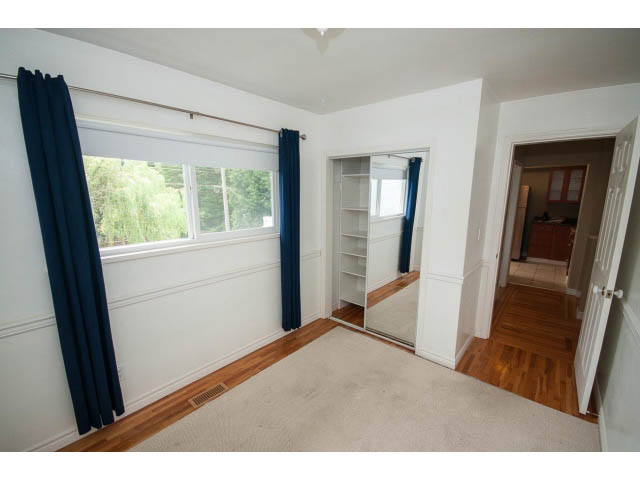 Bright bedroom with hardwood floors and large windows, showcasing a city view. - 549 W Queens, North Vancouver