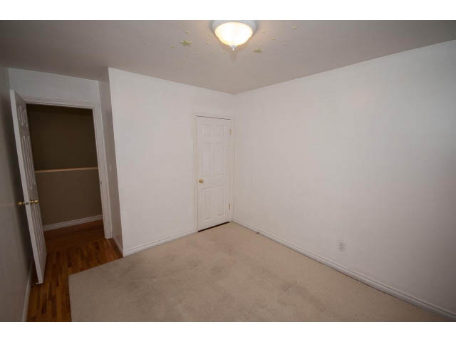 Bright living room with carpeted floor and white walls, leading to a hallway. - 549 W Queens, North Vancouver