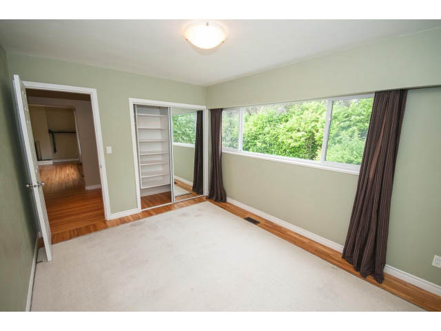 Spacious bedroom with large windows, hardwood floors, and built-in shelves. - 549 W Queens, North Vancouver