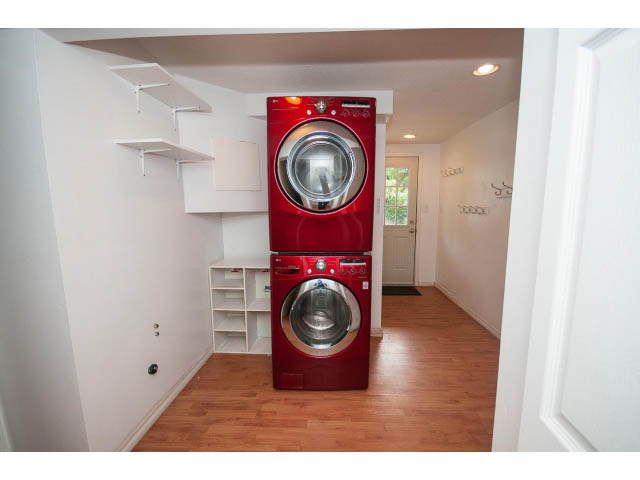 Laundry room with red washer and dryer, hardwood floors, and shelving. - 549 W Queens, North Vancouver