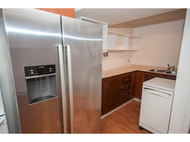 Bright kitchen with stainless steel appliances, hardwood floors, and white cabinetry. - 549 W Queens, North Vancouver