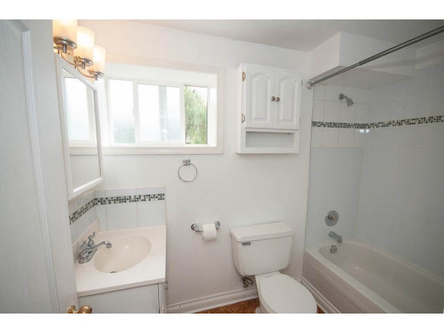 Bright bathroom with white cabinetry and a window. - 549 W Queens, North Vancouver