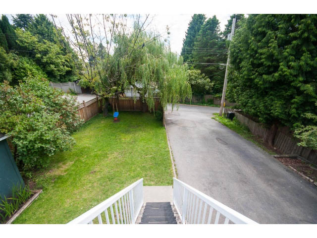 Staircase leading to a lush, green backyard with a willow tree and wooden fence. - 549 W Queens, North Vancouver