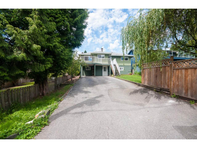 Driveway leading to a 5-bedroom house with a wooden fence and lush greenery. - 549 W Queens, North Vancouver
