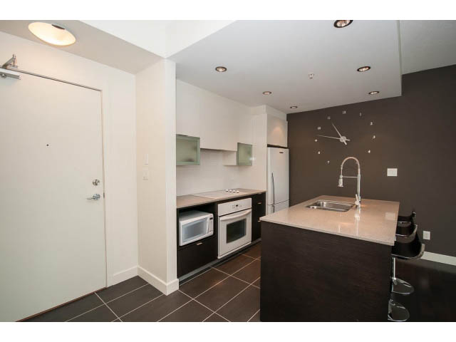 Bright kitchen with white cabinets, dark countertops, and modern appliances. - 1105 - 175 West 2nd Street, North Vancouver