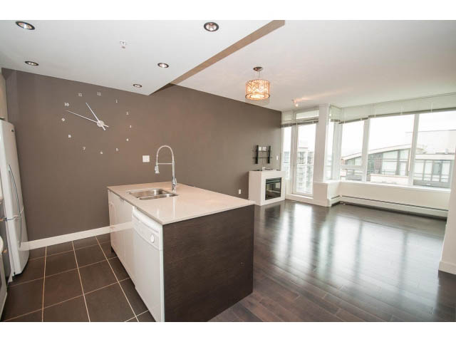 Bright kitchen with white countertops and hardwood floors, city view through large windows. - 1105 - 175 West 2nd Street, North Vancouver