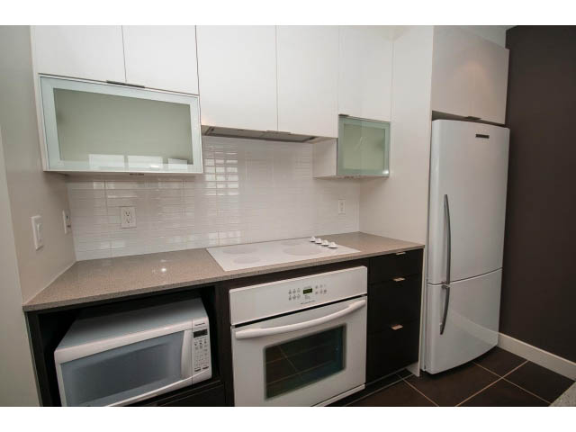 Bright kitchen with white countertops, stainless steel appliances, and dark brown walls. - 1105 - 175 West 2nd Street, North Vancouver