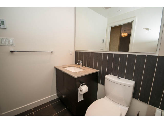 Bathroom with modern sink, dark wood paneling, and large mirror. - 1105 - 175 West 2nd Street, North Vancouver