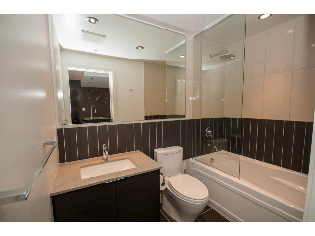 Furnished 1-bedroom condo with modern bathroom, granite countertops, and large mirror. - 1105 - 175 West 2nd Street, North Vancouver