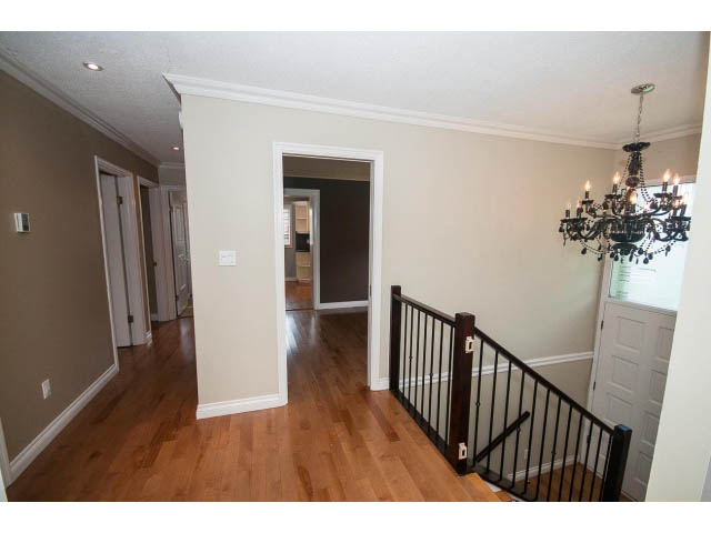 Staircase with black railing leading to upper level; hardwood floors throughout. - Upper - 1998 Cortell St., North Vancouver