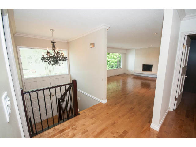 Spacious living room with hardwood floors, chandelier, and large windows. - Upper - 1998 Cortell St., North Vancouver