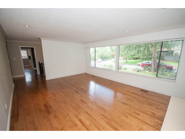 Spacious living room with hardwood floors and large windows showing a view. - Upper - 1998 Cortell St., North Vancouver