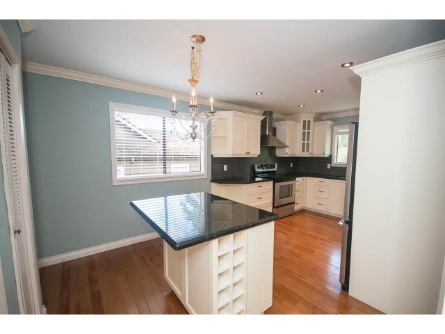 Bright kitchen with white cabinets, hardwood floors, and a chandelier. - Upper - 1998 Cortell St., North Vancouver
