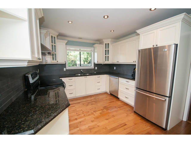 Bright kitchen with black granite countertops, hardwood floors, and stainless steel appliances. - Upper - 1998 Cortell St., North Vancouver