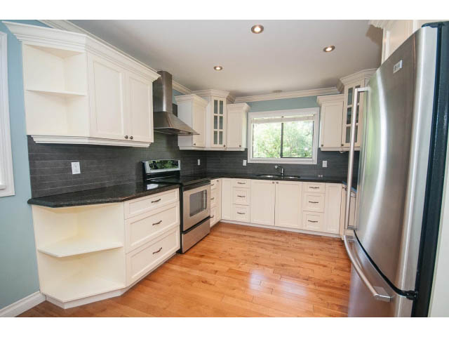Bright kitchen with white cabinets, black countertops, and hardwood floors. - Upper - 1998 Cortell St., North Vancouver