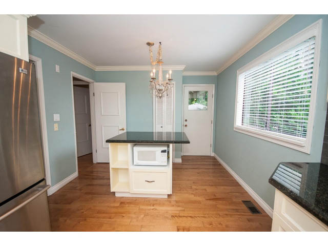 Bright kitchen with hardwood floors, granite countertops, and a chandelier, leading to a cozy dining area. - Upper - 1998 Cortell St., North Vancouver
