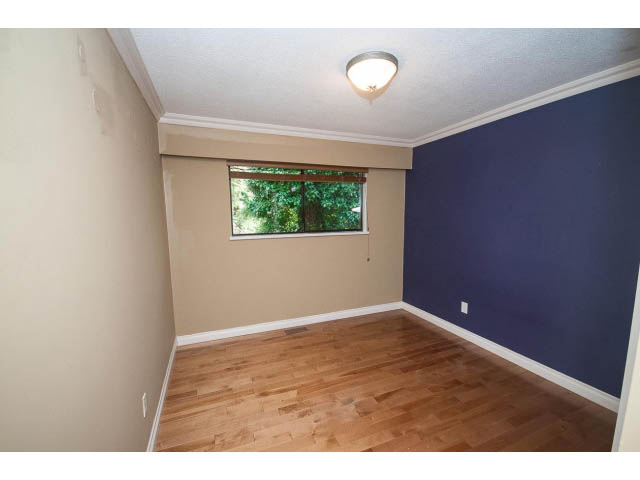 Den with hardwood floors and a large window showing greenery. - Upper - 1998 Cortell St., North Vancouver