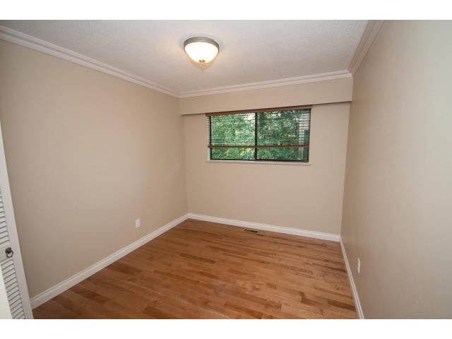 Den with hardwood floors and a window view, neutral walls, and a ceiling light. - Upper - 1998 Cortell St., North Vancouver