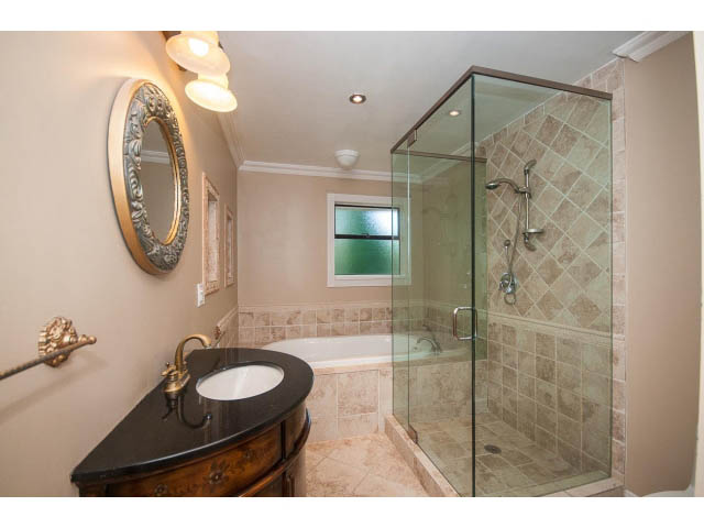 Spacious bathroom with a glass shower and black countertop. - Upper - 1998 Cortell St., North Vancouver