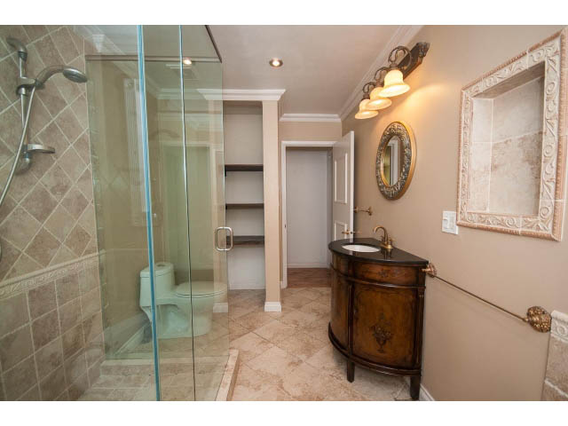 Spacious bathroom with marble countertops, wooden vanity, and a glass shower. - Upper - 1998 Cortell St., North Vancouver