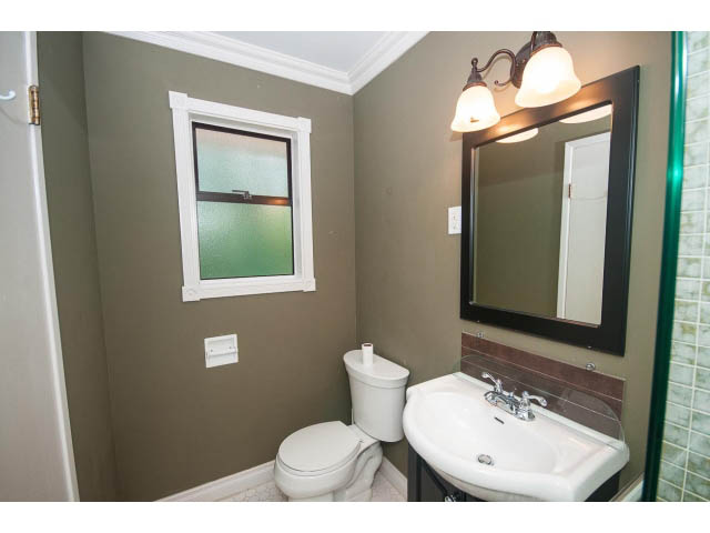 Small bathroom with white fixtures, green walls, and a frosted window. - Upper - 1998 Cortell St., North Vancouver