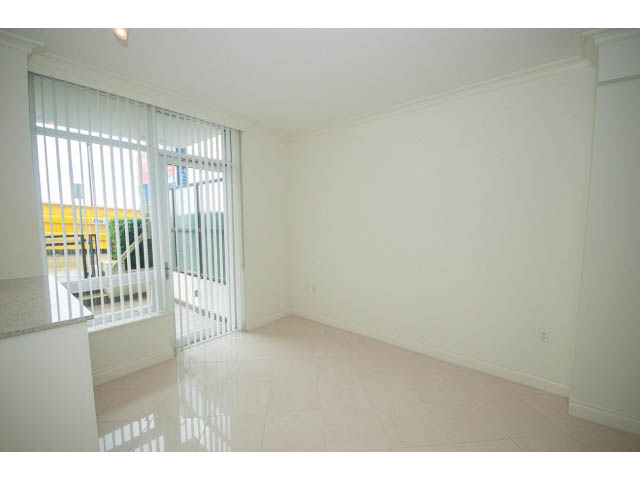 Bright living room with large windows, white walls, and glossy tile floors. - 203 - 162 Victory Ship Way, North Vancouver