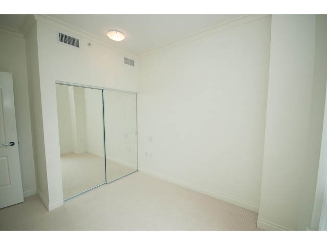 Bright bedroom with mirrored closet doors and white walls. - 203 - 162 Victory Ship Way, North Vancouver