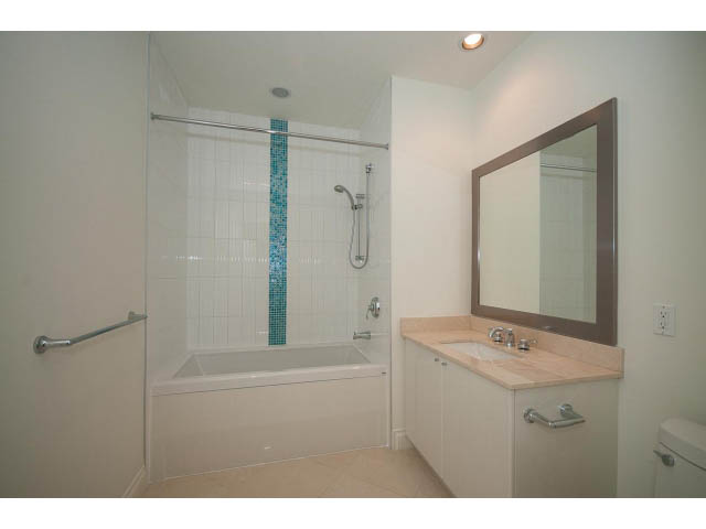 Furnished 1-bedroom condo bathroom with light wood countertops and a glass shower. - 203 - 162 Victory Ship Way, North Vancouver