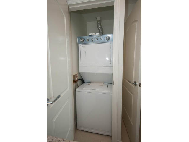 Bright laundry room with white appliances and a door leading to another space. - 203 - 162 Victory Ship Way, North Vancouver