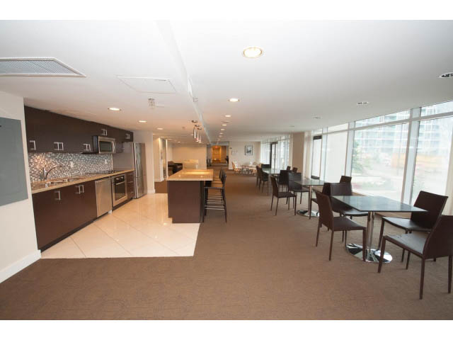 Furnished living room with large windows, city view, and modern furniture. - 203 - 162 Victory Ship Way, North Vancouver