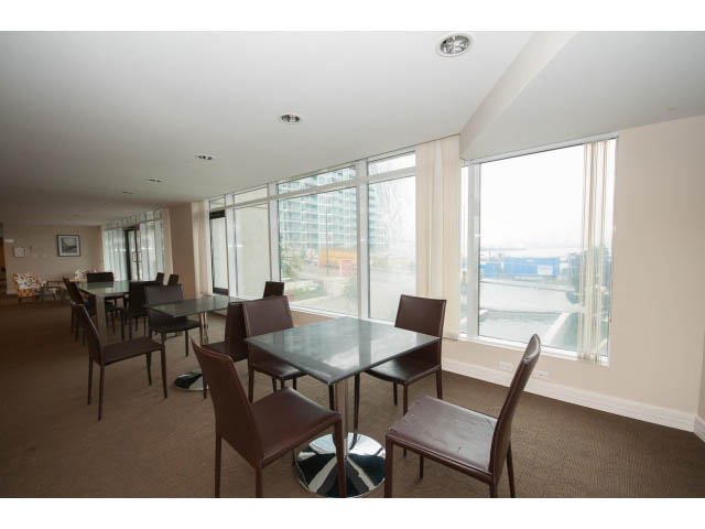 Furnished dining area with large windows and city view. - 203 - 162 Victory Ship Way, North Vancouver