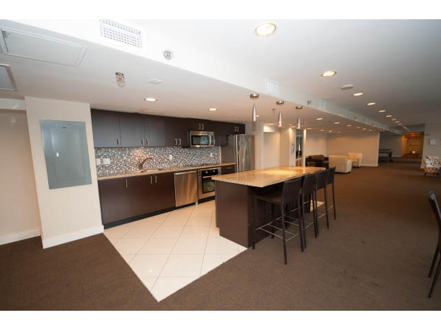 Bright kitchen with granite countertops and modern appliances, open to a cozy living area with a dining table.